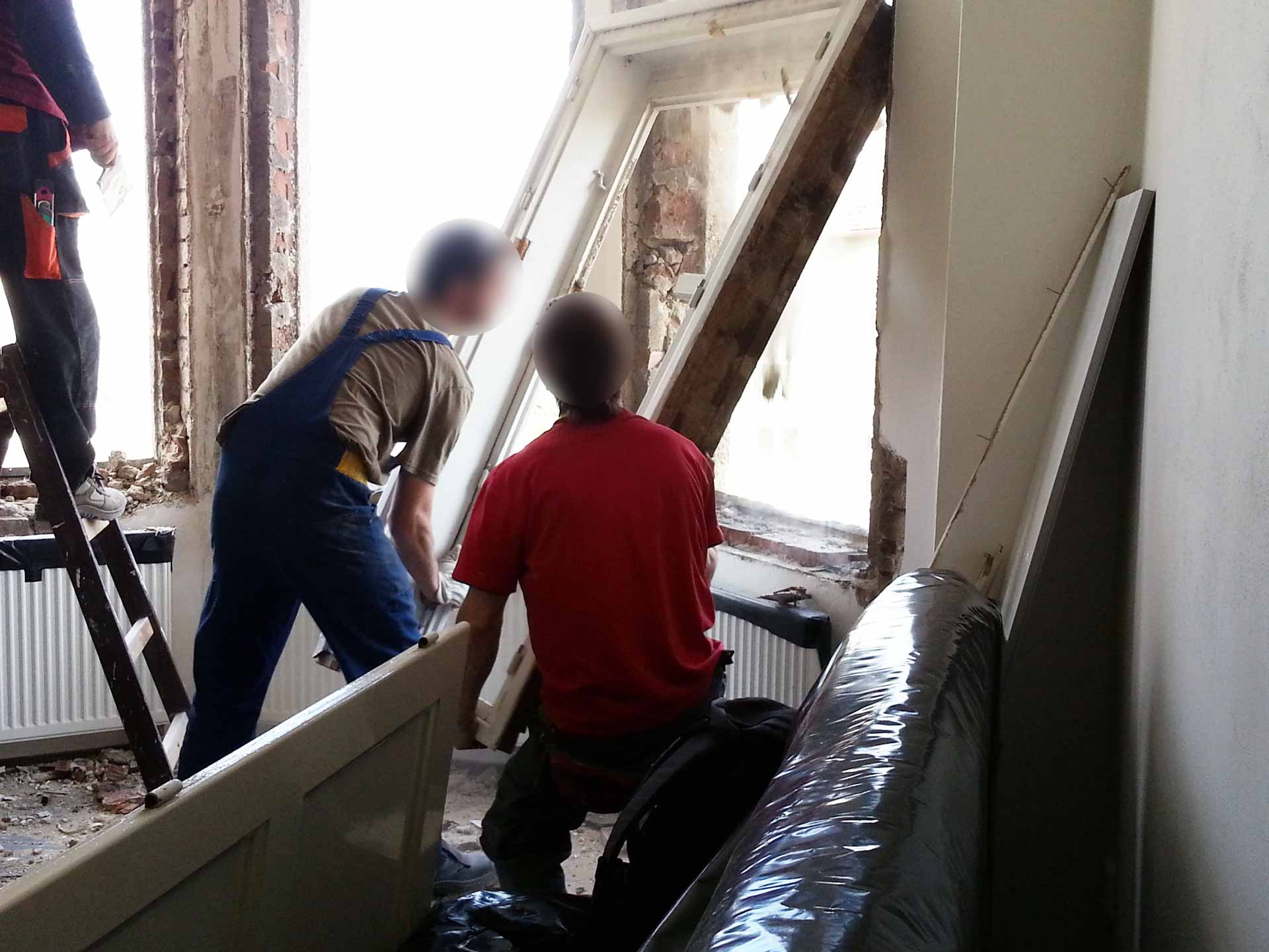 Dělníci vytahují staré kastlové okno ze špalety. Dělníci vytahují staré kastlové okno ze špalety.